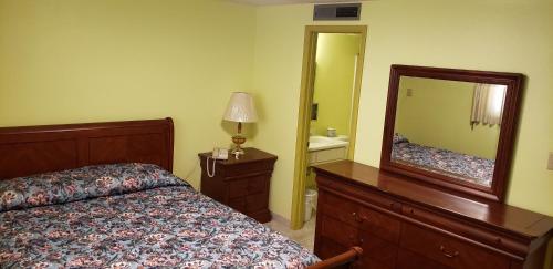 a bedroom with a bed and a dresser and a mirror at Westernaire Motel in Mesa