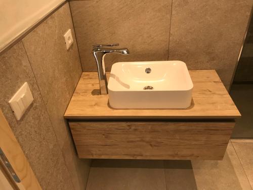 a bathroom with a white sink on a wooden counter at Ciasa De Rosa in Pozza di Fassa