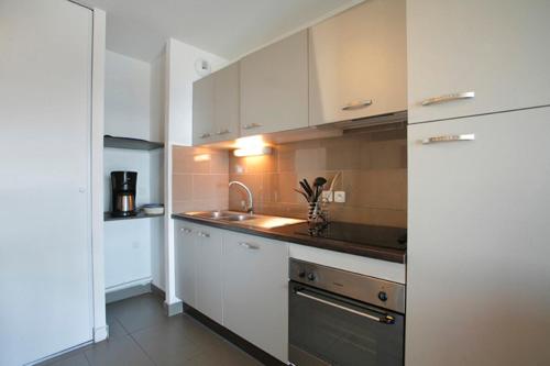 a kitchen with white cabinets and a sink at Résidence Le Pic de l'Ours in Font-Romeu