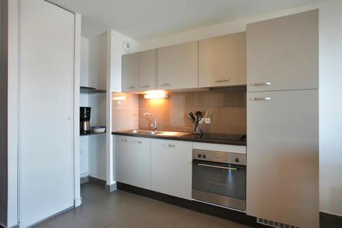 a kitchen with white cabinets and a sink at Résidence Le Pic de l'Ours in Font-Romeu