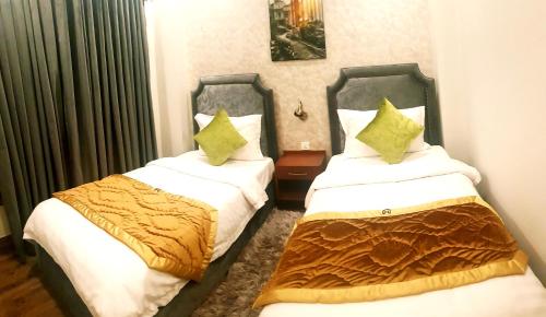 two beds in a hotel room withskirts at Hayyat Luxury Hotel Apartments in Lahore
