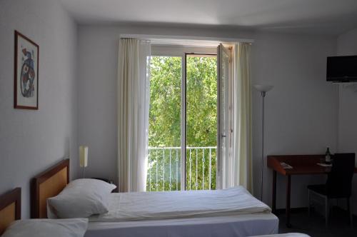 a bedroom with a bed and a large window at Hotel Landhus in Zürich