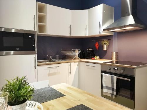 une cuisine avec des armoires blanches et une table en bois dans l'établissement Au p'tit Cordonnier, à Colmar