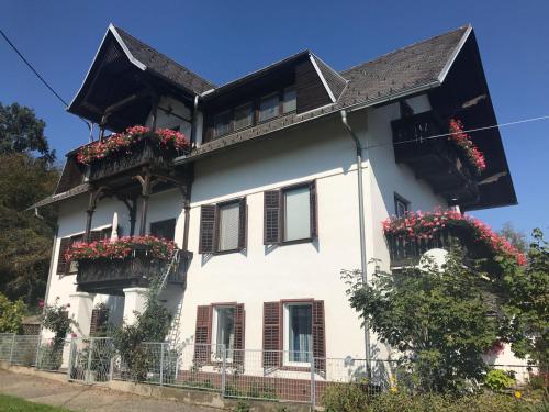 a white house with flowers in the balconies at Villa Nusswald in Krumpendorf am Wörthersee
