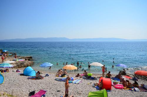 a group of people sitting on a beach at Apartment Andreas in Ravni