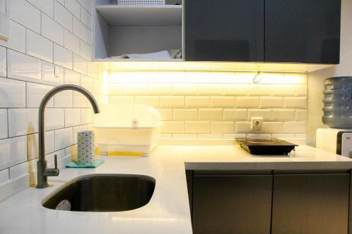 a kitchen with a sink and a counter with lights at 1BR Brooklyn Alam Sutera Apartment near BINUS By Travelio in Dongkal Dua