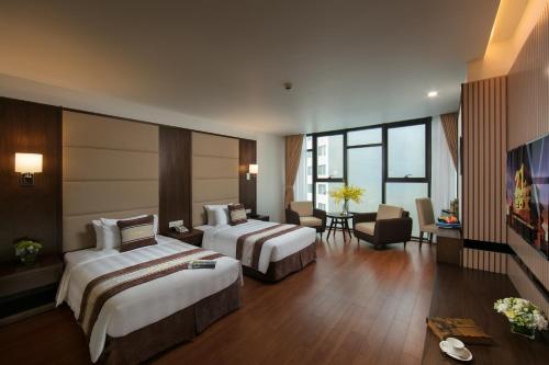a hotel room with two beds and a living room at Ha Long Marina Hotel in Ha Long