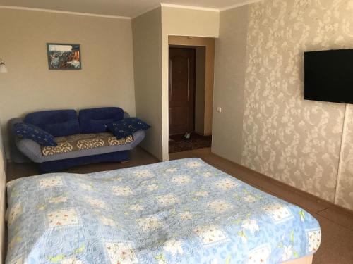 a bedroom with a bed and a couch and a television at Apartment on Amurskiy Bulvar 62 in Khabarovsk