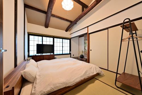 a bedroom with a large bed and a flat screen tv at Luxury Machiya Takeya Nishijin in Kyoto