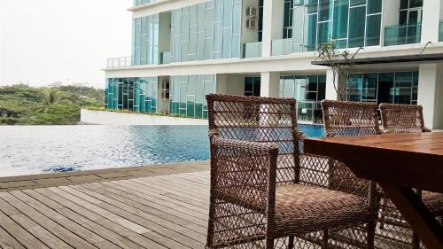 a wooden deck with chairs and a table next to a building at Brooklyn Alam Sutera Studio Apartment with Sofa Bed By Travelio in Dongkal Dua