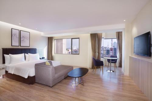 a hotel room with a bed and a couch and a table at AIHO Hotel Medan in Medan