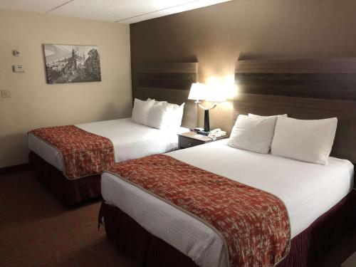 a hotel room with two beds and a lamp at MHO INN and SUITES in Monmouth Junction