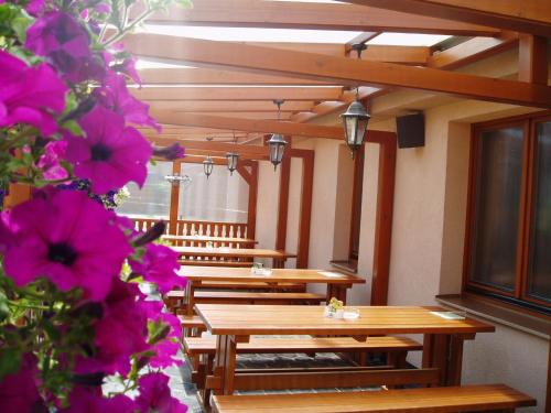 a row of tables and benches in a room with flowers at Penzion U Vlků in Valtice