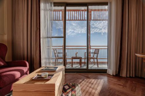 a living room with a table and a large window at Taj Theog Resort & Spa Shimla in Shimla
