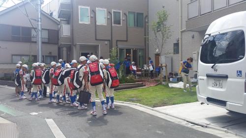 a group of people with backpacks walking down a street at Tokyo Guest House 2020 in Tokyo