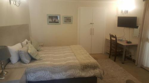 a bedroom with a bed and a table and a desk at 12 On Vaal Drive Guesthouse in Vanderbijlpark