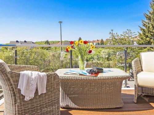 una mesa con sillas y un jarrón de flores en el balcón en Auszeit Luxusappartment mit Meerblick und Infrarot Kabine, en Sassnitz