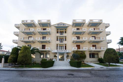 un grand bâtiment jaune avec des arbres devant lui dans l'établissement Olympion, à Athènes