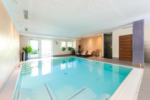 a large swimming pool in a house with blue water at Business Resort Parkhotel Werth in Bolzano