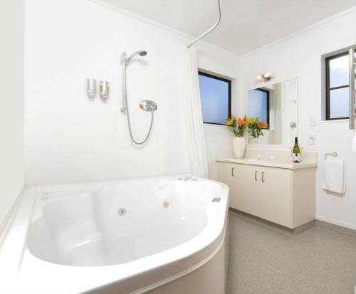 Baño blanco con bañera y lavamanos en Knightsbridge Court Motor Lodge, en Blenheim