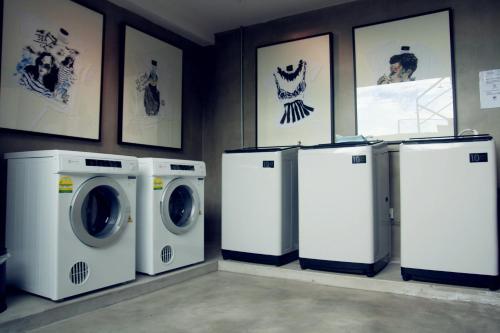 a laundry room with three washing machines and pictures on the wall at M Roof Hotel & Residences in Ipoh