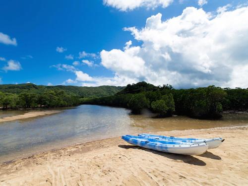 a boat sitting on a sandy beach next to a river at Sun Green Resort Hotel Ishigaki in Ishigaki Island