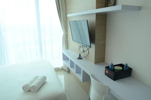 a white room with a white bed and a tv at Brand New Studio Tree Park City BSD Apartment near ICE BSD By Travelio in Serpong