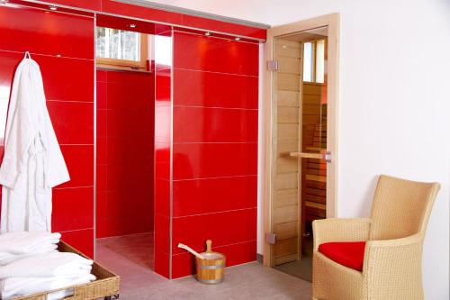 a red bathroom with a shower and a chair at Hotel Vier Jahreszeiten am Schluchsee in Schluchsee