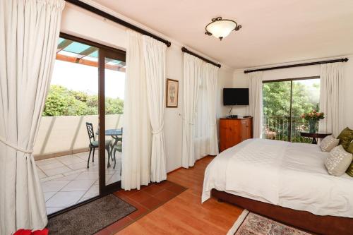 a bedroom with a bed and a balcony at A Tuscan Villa Guest House in Fish Hoek