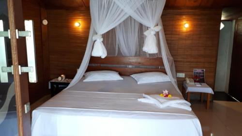 a bedroom with a white bed with a canopy at Pele's Place in Sabong