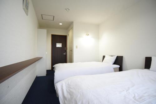two beds in a hotel room with white sheets at Alaise De Bale Shirahama in Shirahama