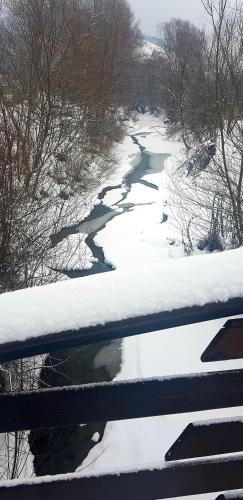a river with snow on the ground next to a fence at Pensiunea Marinela in Sighetu Marmaţiei