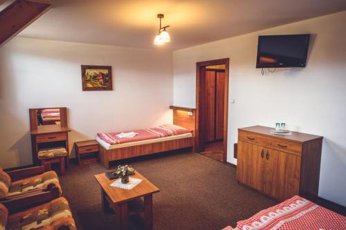 a living room with a bed and a couch and a tv at Penzion Pribisko in Zuberec