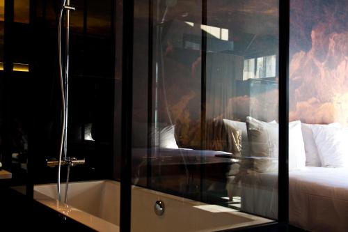 a bedroom with a bed and a tub in a room at HotelO Kathedral in Antwerp