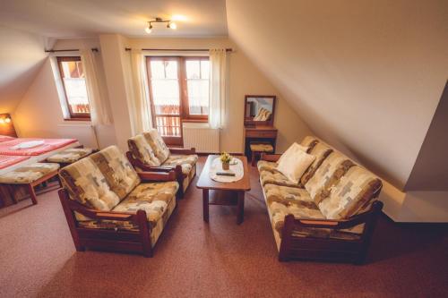 a living room with couches and a table and a bed at Penzion Pribisko in Zuberec