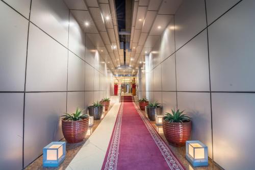 a long corridor with potted plants in a building at Al Muhaidb Al Takhassosi Abaqrino in Riyadh