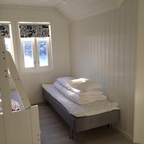 a small room with a bed and two windows at Havbris in Bremnes
