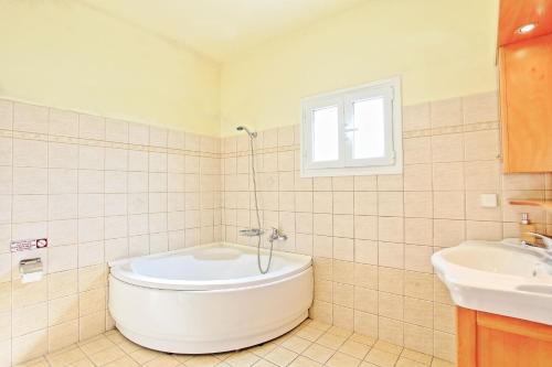 a white bathroom with a tub and a sink at Bella Villa Vasiliki in Litherés