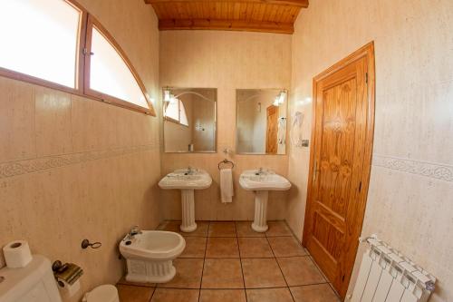 a bathroom with two sinks and a toilet and a mirror at Hotel Alfonso VIII in Santa Elena