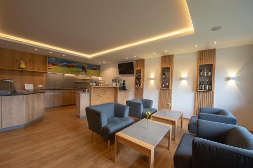 a living room with blue chairs and a kitchen at Frühstückspension Ochnerbauer in Kindberg