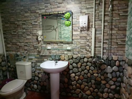La salle de bains en pierre est pourvue de toilettes et d'un lavabo. dans l'établissement Jinsha Old Street B&B, à Nangan