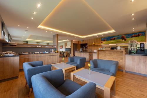 a restaurant with blue chairs and tables and a kitchen at Frühstückspension Ochnerbauer in Kindberg