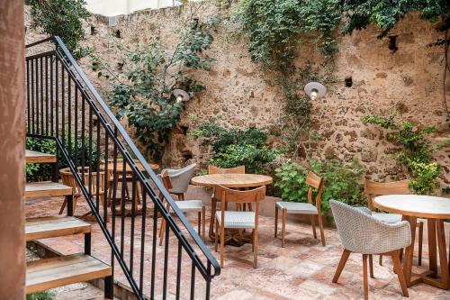 un patio con mesas, sillas y una pared en Hotel Off en La Canea