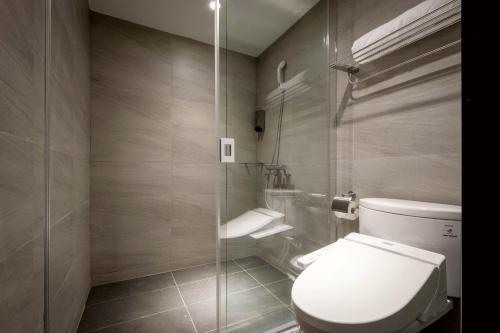 a bathroom with a toilet and a glass shower at D D Hotel in Tainan