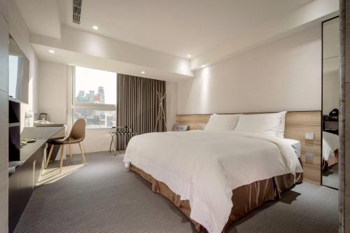 a bedroom with a large white bed and a desk at D D Hotel in Tainan