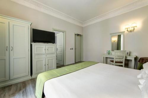a white bedroom with a bed and a flat screen tv at BB Hotels Smarthotel Bailey's in Rome