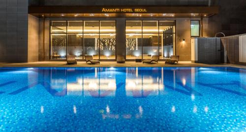 a hotel swimming pool with chairs in front of a building at Amanti Hotel Seoul in Seoul