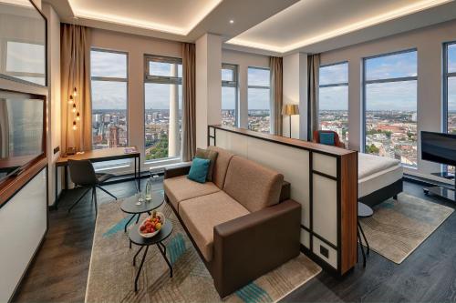 a hotel room with a couch and a bed and windows at Park Inn by Radisson Berlin Alexanderplatz in Berlin