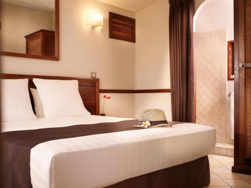 a hotel room with a bed with a hat on it at Iloha Seaview Hotel in Saint-Leu