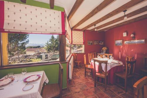 a restaurant with two tables and a large window at Hotel Rural La Dehesilla in Barajas de Gredos